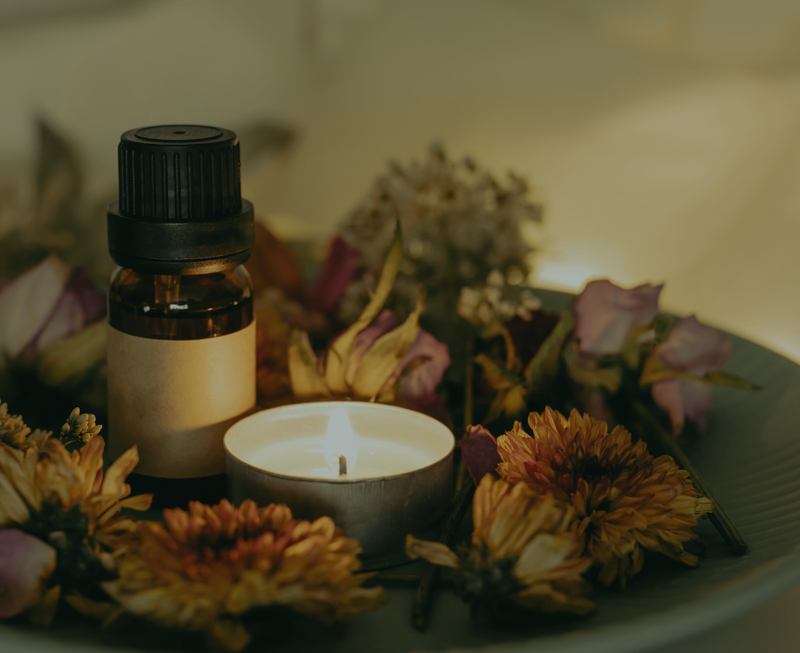 essential oil by dried flowers and a tealight candle